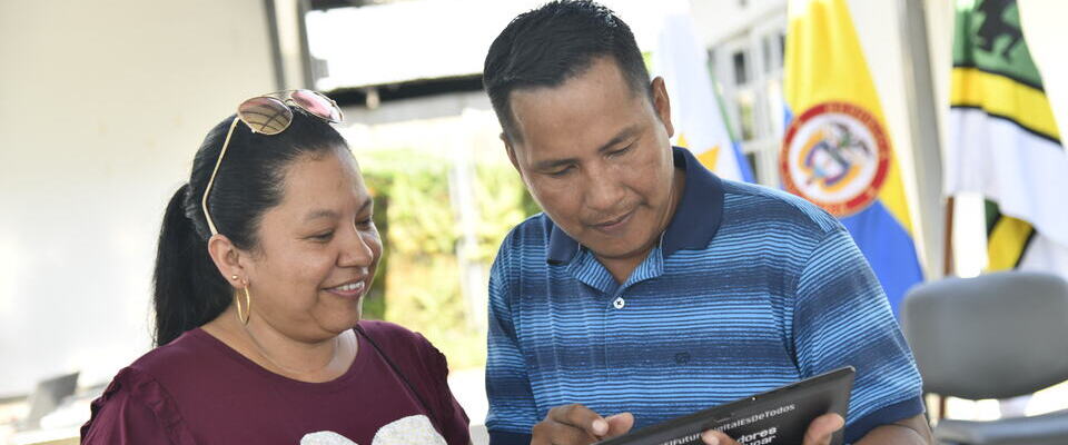 Foto de una señora y un señor observando una tablet